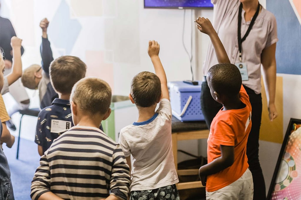 a classroom with students raising their hands